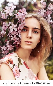 Portrait Of A Young Girl In A Blouse With A Print Of Flowers On A Lilac Background. Natural Face. Portrait In The Spring.