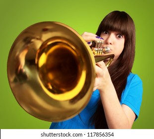 portrait of a young girl blowing trumpet on green background