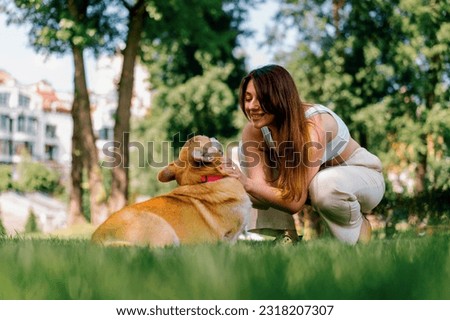 portrait of a young girl and a cute corgi dog, the owner kisses the dog on the nose on a walk in park