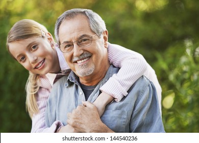 Portrait of young girl embracing grandfather from behind in backyard - Powered by Shutterstock