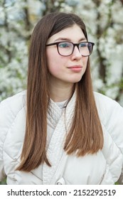 Portrait Of Young Girl In Glasses Near Flowering Tree. Long Healthy Hair. Spring Season. Vertical