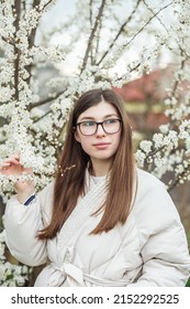 Portrait Of Young Girl In Glasses Near Flowering Tree. Long Healthy Hair. Spring Season.