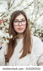 Portrait Of Young Girl In Glasses Near Flowering Tree. Long Healthy Hair. Spring Season.