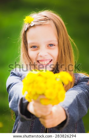 Portrait of young girl holding bouquet of flowers in hands. Happy kid. Girl with yellow dandelions. Smiling face of teenager with long hear. Vertical color photo.