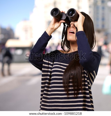 portrait of a young girl looking through binoculars at a city