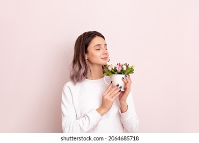 Portrait of a young girl model beautiful and natural with a cup of flowers in her hands in the studio