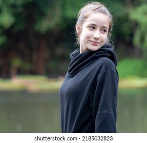 Portrait of young girl smiling. Beautiful woman standing one person outdoor. A cheerful, long brunette-haired, brown eyes female has a positive emotion: freedom of leisure activity in a natural park.