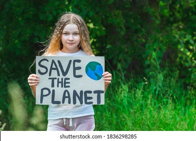 Portrait Of Young Girl Standing With Save The Planet Poster On School Backyard. Piles Of Plastic Garbage On Ground. Teen Kid Child Volunteer Protest Against Earth Pollution, Global Warming, Recycle.