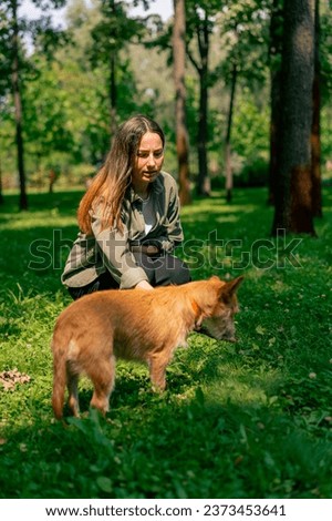 portrait of a young girl walking in the park with her dog, playing with stick and teasing him with it