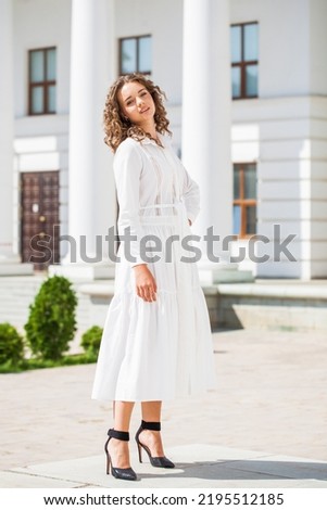 Portrait of a young girl in a white dress posing against the background of the Orthodox Cathedral