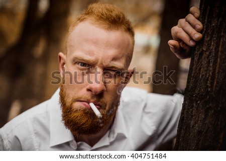 portrait of young grumpy bearded red hair man with sigaret horizontal