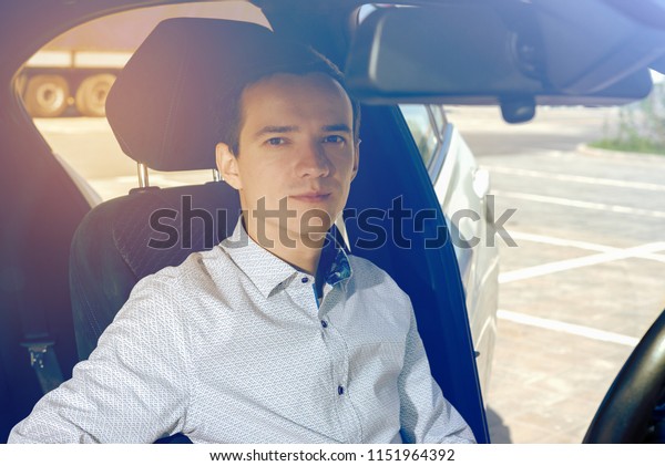 portrait of young guy in the\
car driving outside the glass. concept of a successful business.\
toned