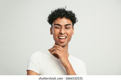 Portrait of a young guy looking happy on white background. Gender fluid young man laughing on white background.