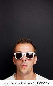 portrait of a young guy with white sunglasses in front of a chalkboard