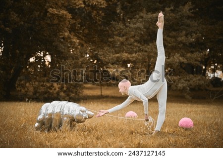 Portrait of young hairless girl ballerina with alopecia in white cloth playing with tardigrade toy in fall park, surreal scene with bald teenage girl reflect on intertwining threads of life and art