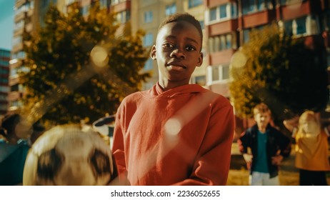 Portrait of a Young Handsome Black Boy Holding a Soccer Ball while Looking at Camera and Smiling. African Kid Standing in Backyard Together with Friends. Concept of Sports, Childhood, Friendship. - Shutterstock ID 2236052655