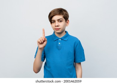 Portrait Of A Young Handsome Boy 12-14 Years Wearing Casual Clothes Pointing Finger Up With Successful Idea. Showing Number One. Studio Shot, White Background, Isolated