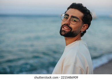 A portrait of a young and handsome Caucasian man posing for the camera at the beach, smiling and enjoying the sunset. - Powered by Shutterstock