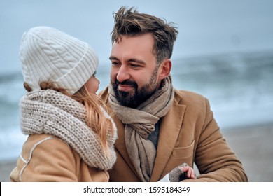 Portrait of a young handsome dad with his beloved pretty daughter on the beach in winter.