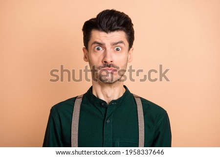 Portrait of young handsome funky shocked amazed doubtful man bite lips having problem isolated on beige color background