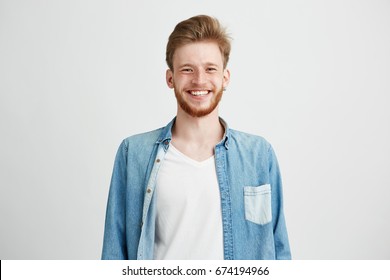 Portrait of young handsome hipster man with beard smiling laughing looking at camera over white background.