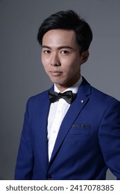 portrait of a young handsome man with bow tie on gray background 
