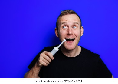 Portrait of a young handsome man brushing his teeth with an ultrasonic modern toothbrush. Oral care. Morning self care - Shutterstock ID 2253657711