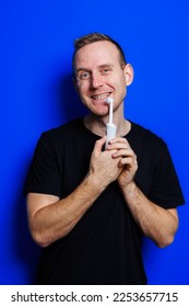 Portrait of a young handsome man brushing his teeth with an ultrasonic modern toothbrush. Oral care. Morning self care - Shutterstock ID 2253657715