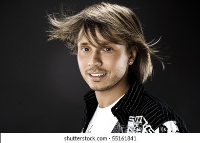 Portrait Of Young Handsome Man With Hair Fluttering In The Wind On Black Background In The Studio