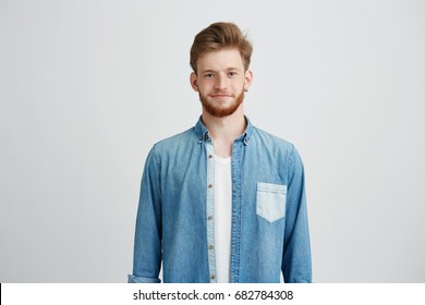 Portrait of young handsome man in jean shirt smiling looking at camera over white background.