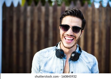 Portrait Of A Young Handsome Man With Toupee And Headphones In Urban Background