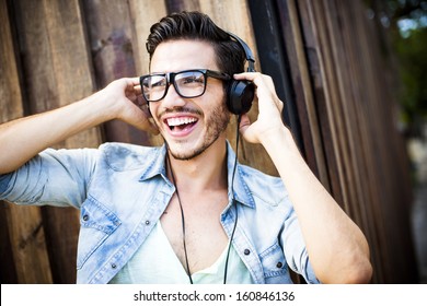 Portrait of a young handsome man with toupee and headphones in urban background