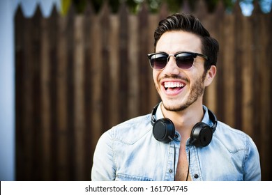 Portrait Of A Young Handsome Man With Toupee And Headphones In Urban Background