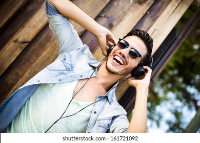 Portrait Of A Young Handsome Man With Toupee And Headphones In Urban Background