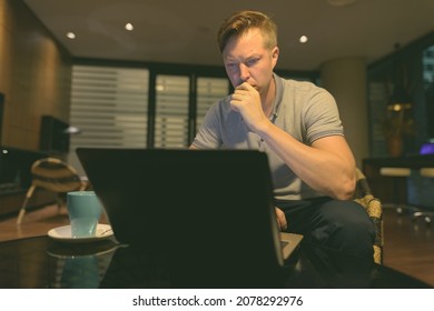 Portrait of young handsome man using laptop in the living room - Shutterstock ID 2078292976