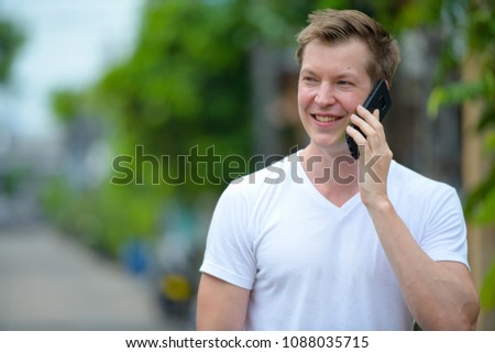 Portrait of young handsome man using mobile phone in the streets outdoors