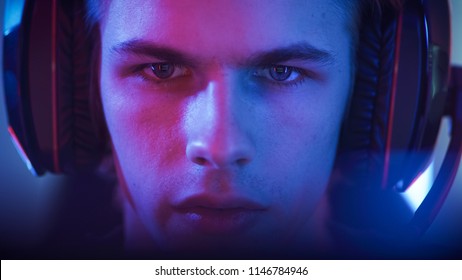 Portrait of the Young Handsome Pro Gamer Playing in Online Video Game. Neon Colored Room. e-Sport Cyber Games Internet Championship.