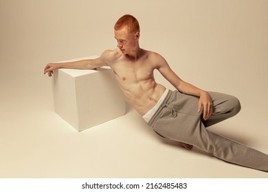 Portrait Of Young Handsome Red-haired Man Posing Shirtless In Pants Isolated Over Grey Studio Background. Muscular Skinny Body. Concept Of Male Beauty, Fashion, Men's Health, Wellness, Fitness