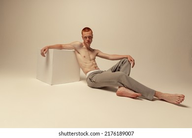 Portrait Of Young Handsome Red-haired Man Posing Shirtless In Pants Isolated Over Grey Studio Background. Concept Of Male Beauty, Fashion, Men's Health, Wellness, Fitness. Model Looking At Camera