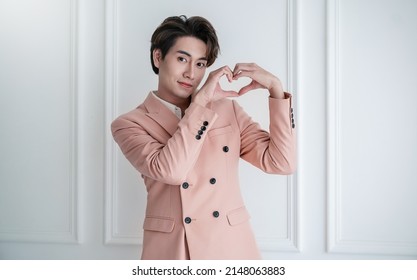 Portrait Of Young Handsome Smile Asian Business Man In Pink Suit Hands Gesture In Heart Shape. Smile Face Asian Guy Model. Japanese Or Korean Boy Lifestyle, Happy Man Valentines Day, Love Concept