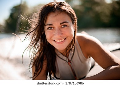 Portrait of young handsome smiling woman with brown eyes and wet hair on blurred background beach
