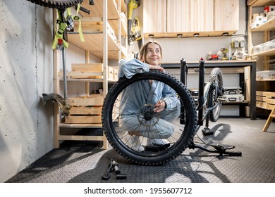 Portrait of a young handywoman reparing her bicycle in the beautiful small workshop at home. DIY concept