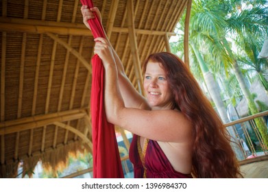 Portrait Of Young Happy And Beautiful Red Hair Woman At Aerial Dancing Workshop Learning Aero Dance Holding Silk Fabric Smiling Cheerful In Tropical Wooden Hut