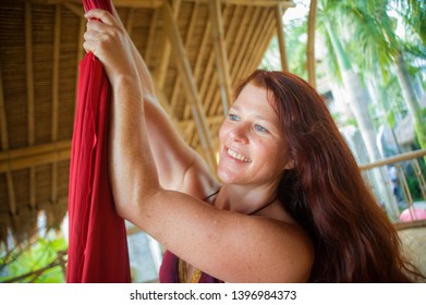 Portrait Of Young Happy And Beautiful Red Hair Woman At Aerial Dancing Workshop Learning Aero Dance Holding Silk Fabric Smiling Cheerful In Tropical Wooden Hut