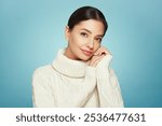 Portrait of young happy beautiful woman smiling and looking away, isolated on blue background in a warm white sweater. Concept of winter promo sale