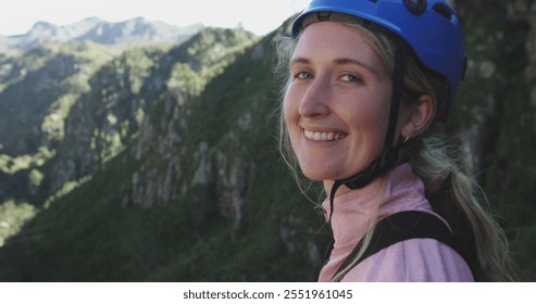 Portrait of a young happy Caucasian woman in helmet admiring the view while out zip lining on sunny day in mountains, slow motion. Adventure Vacation in South Africa - Powered by Shutterstock