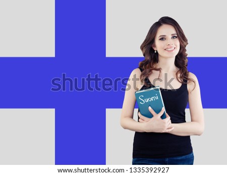 Portrait of young happy cheerful woman with book on the Finnish flag. Beautiful girl learning finnish language