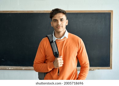 Portrait Of Young Happy Confident Indian Latin Hispanic High School College University Student Standing In Classroom On Black Board Background, Holding Backpack On Shoulder Looking At Camera.