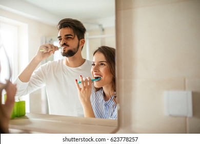 Portrait of young happy couple brushing teeth in the bathroom. - Powered by Shutterstock