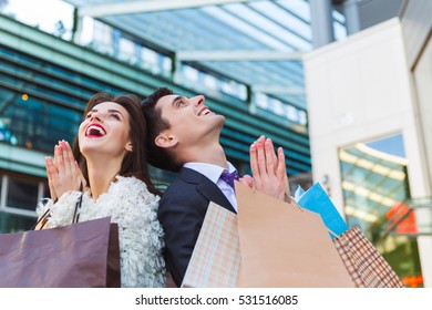 Portrait Of Young Happy Couple With Shopping Bags Praying Outdoor